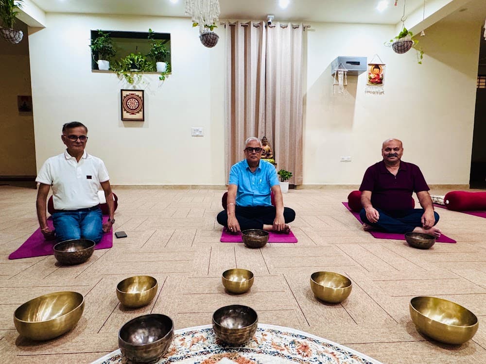 Minimalist wellness studio with Buddha statue, hanging plants, and bronze singing bowls